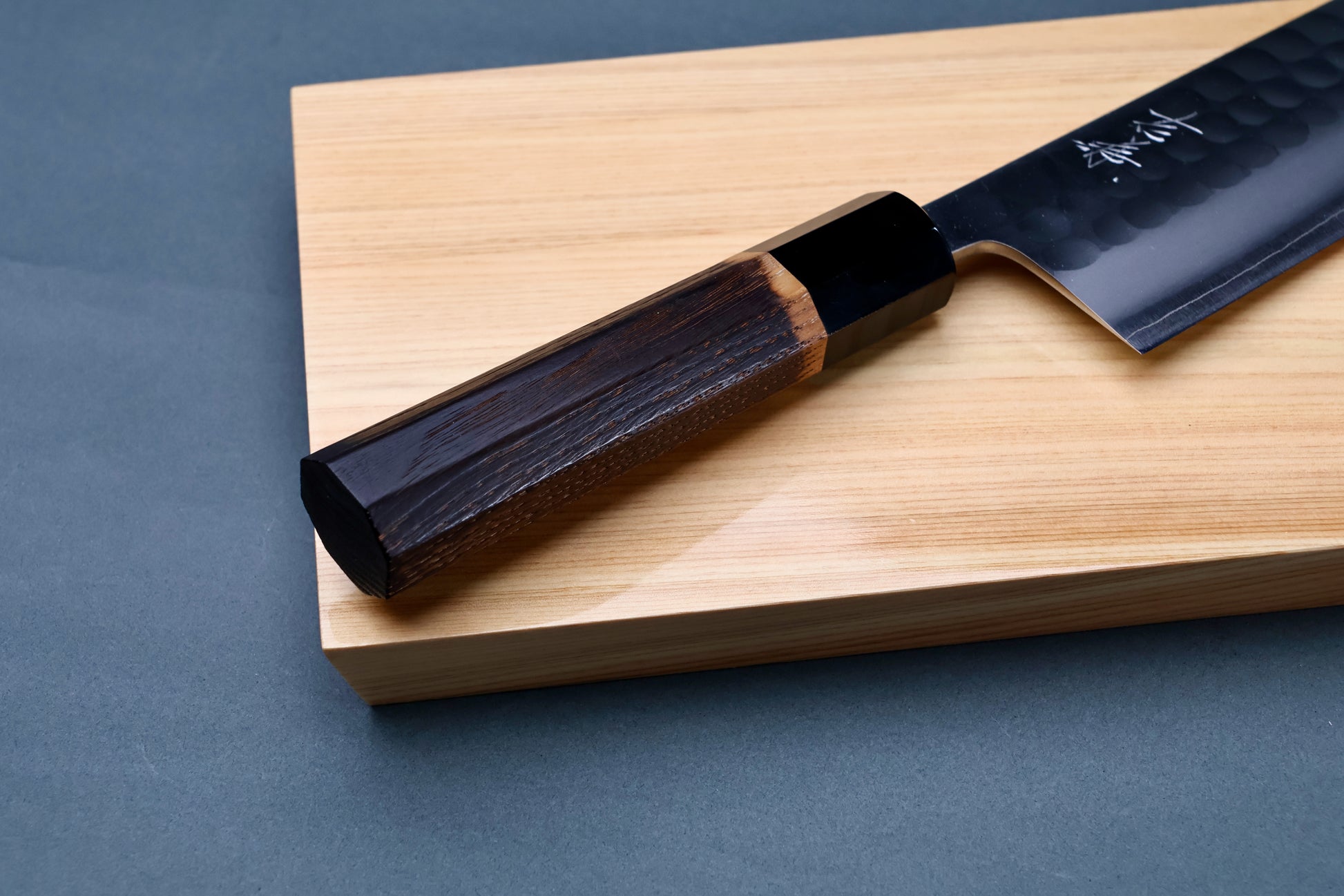 Yoshikane SKD Tsuchime Nakiri 165mm handle close-up on hinoki board showing burnt chestnut wood and buffalo horn collar