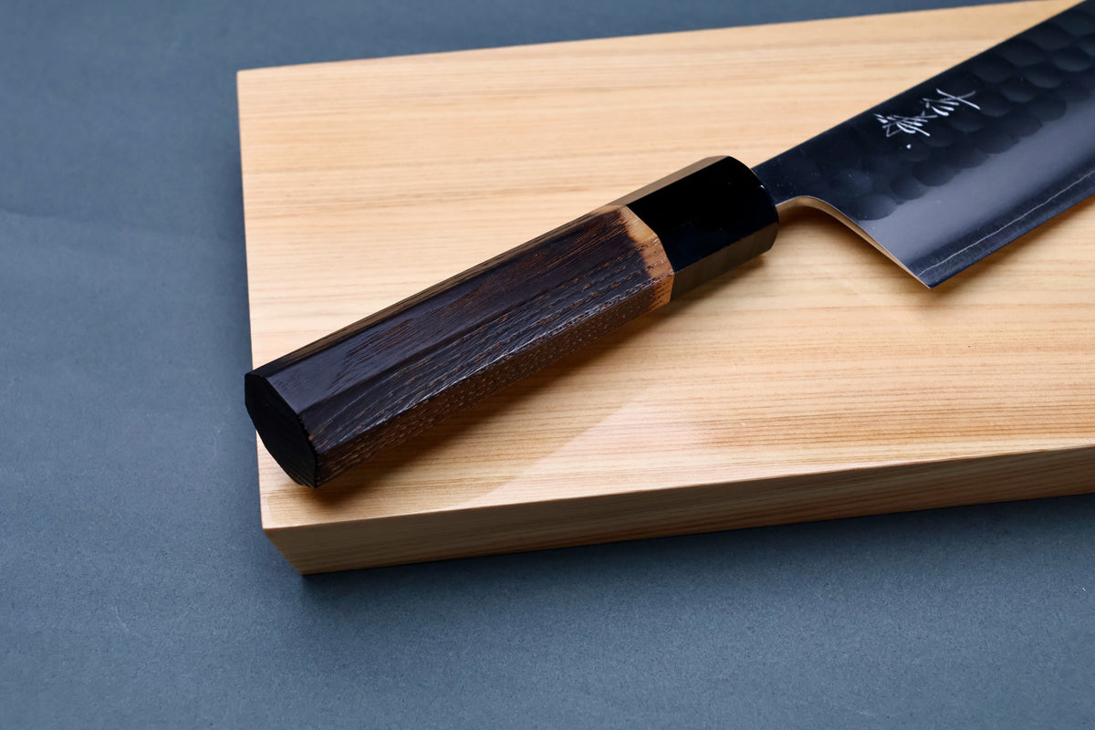 Yoshikane SKD Tsuchime Nakiri 165mm handle close-up on hinoki board showing burnt chestnut wood and buffalo horn collar
