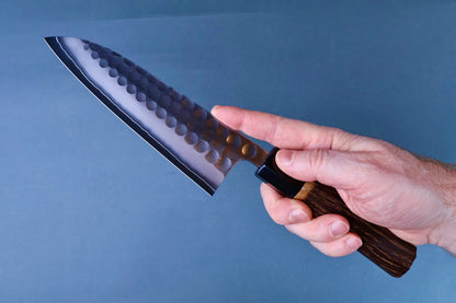 Hand holding Yoshikane SKD Tsuchime Santoku 165mm in pinch grip showing wide santoku blade shape