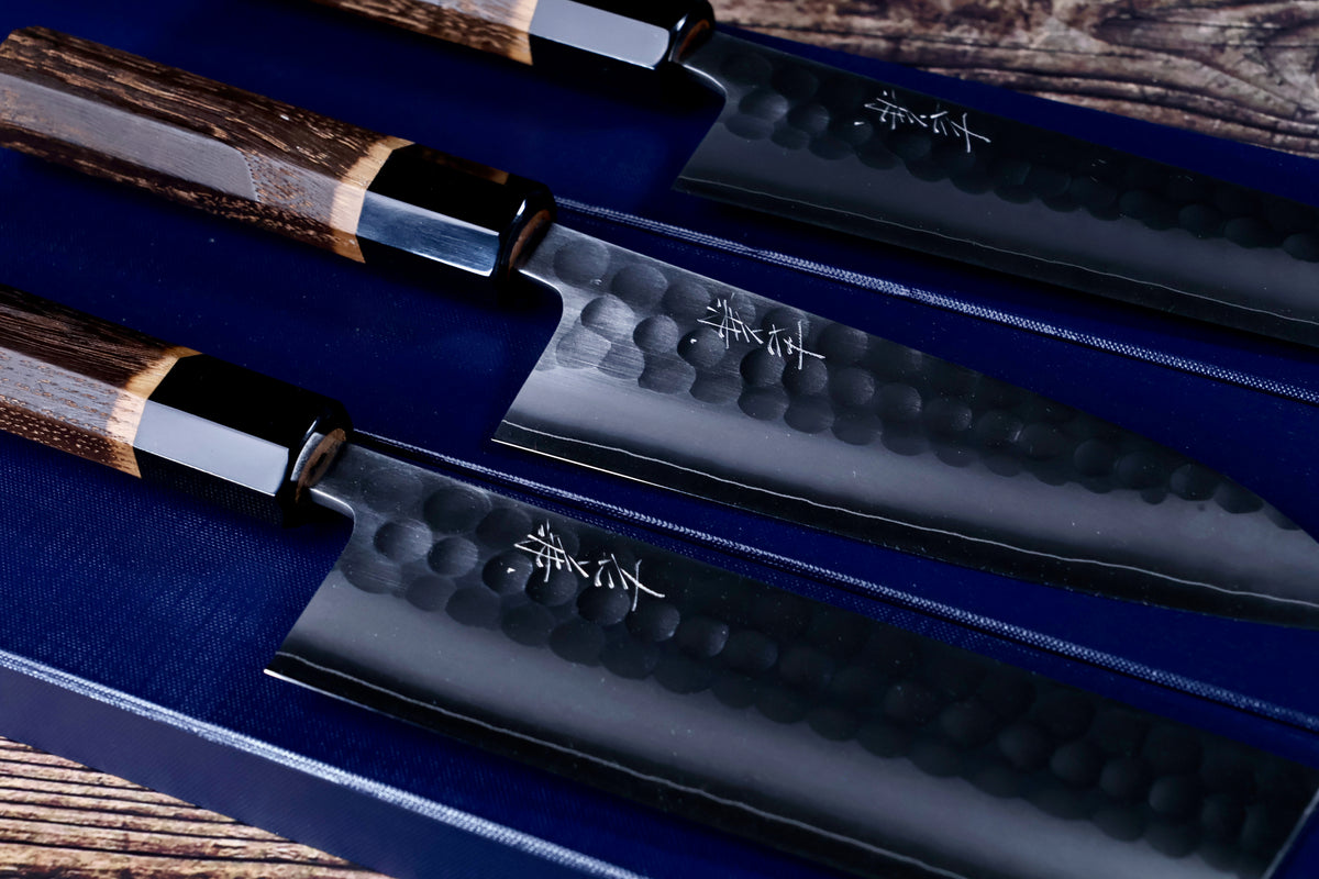 Yoshikane SKD Tsuchime gyuto, santoku and nakiri laid out together on navy cloth showing full knife range